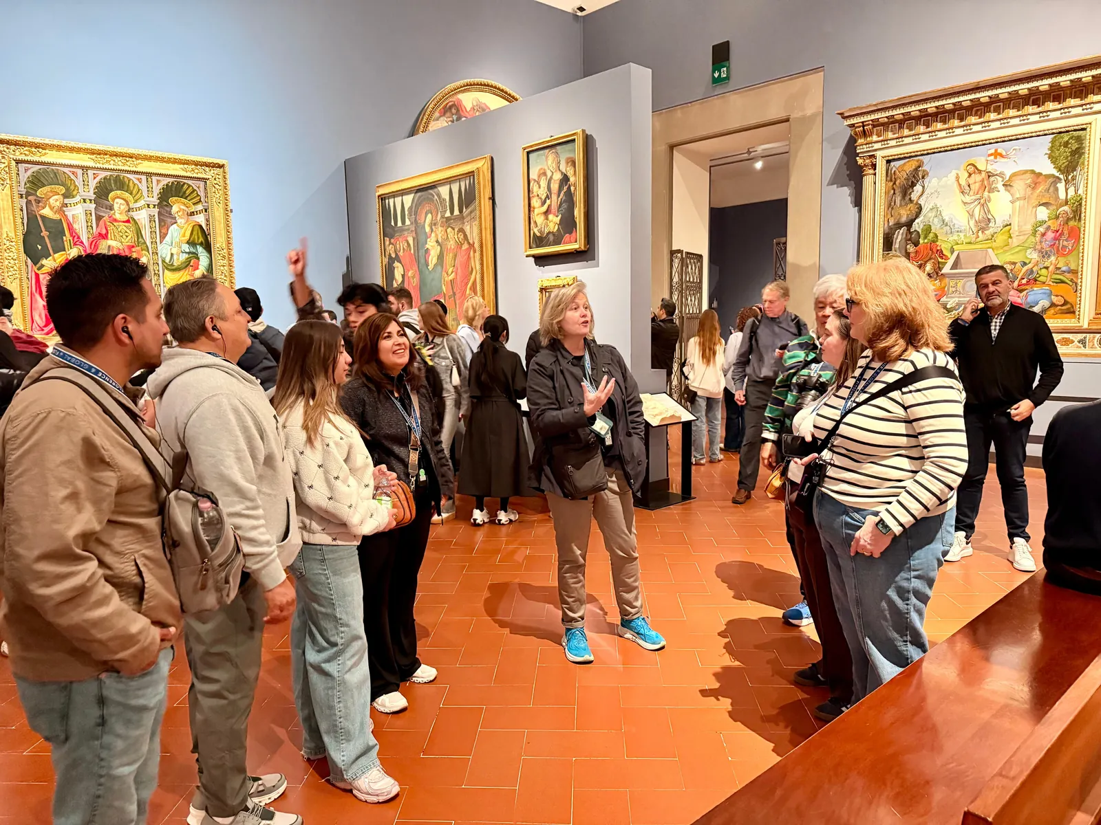 Small group listening to their guide in an early Renaissance room of the Uffizi
