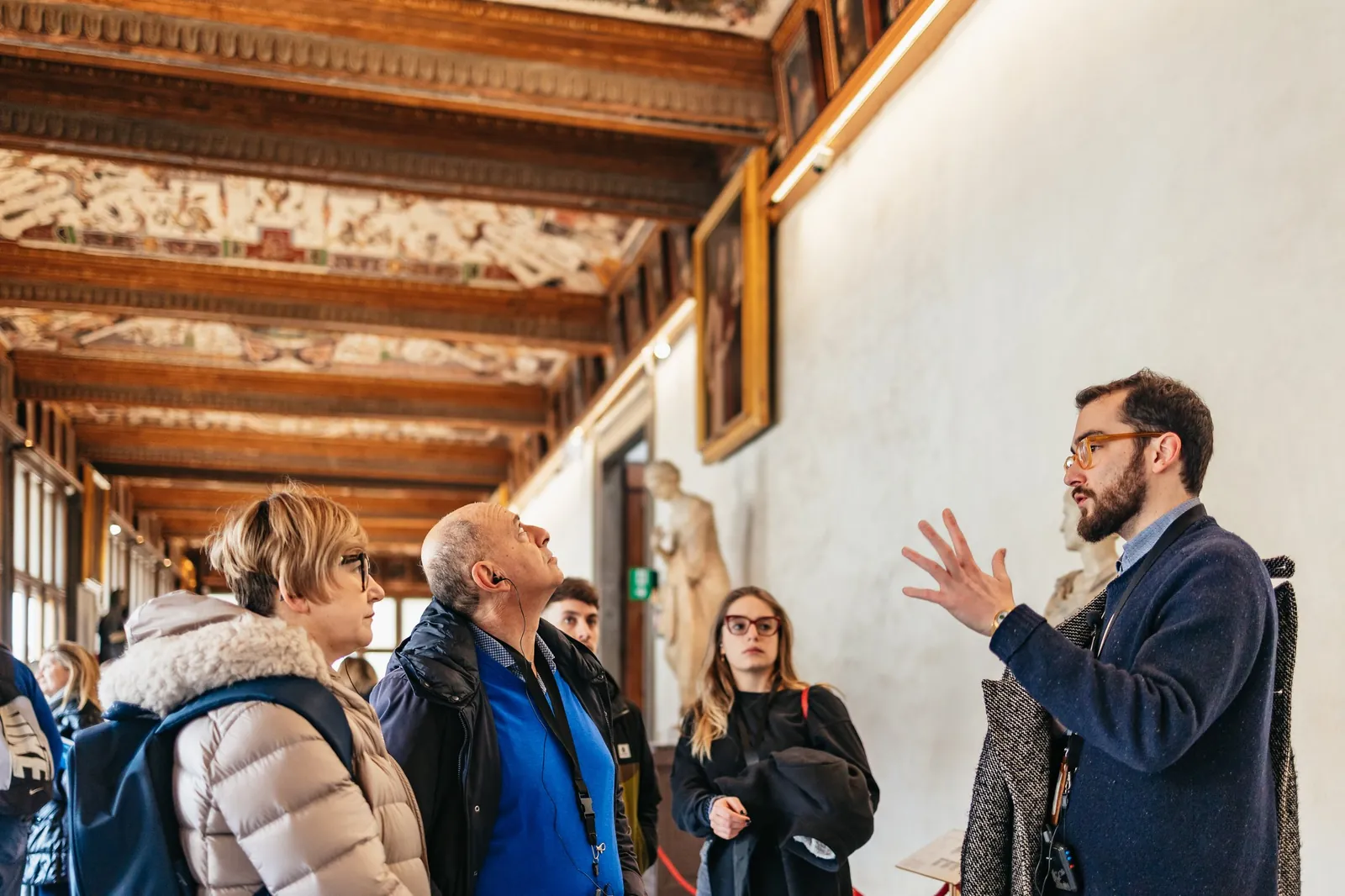 Guide explaining Renaissance art to a small group under the Uffizi's painted corridor ceiling