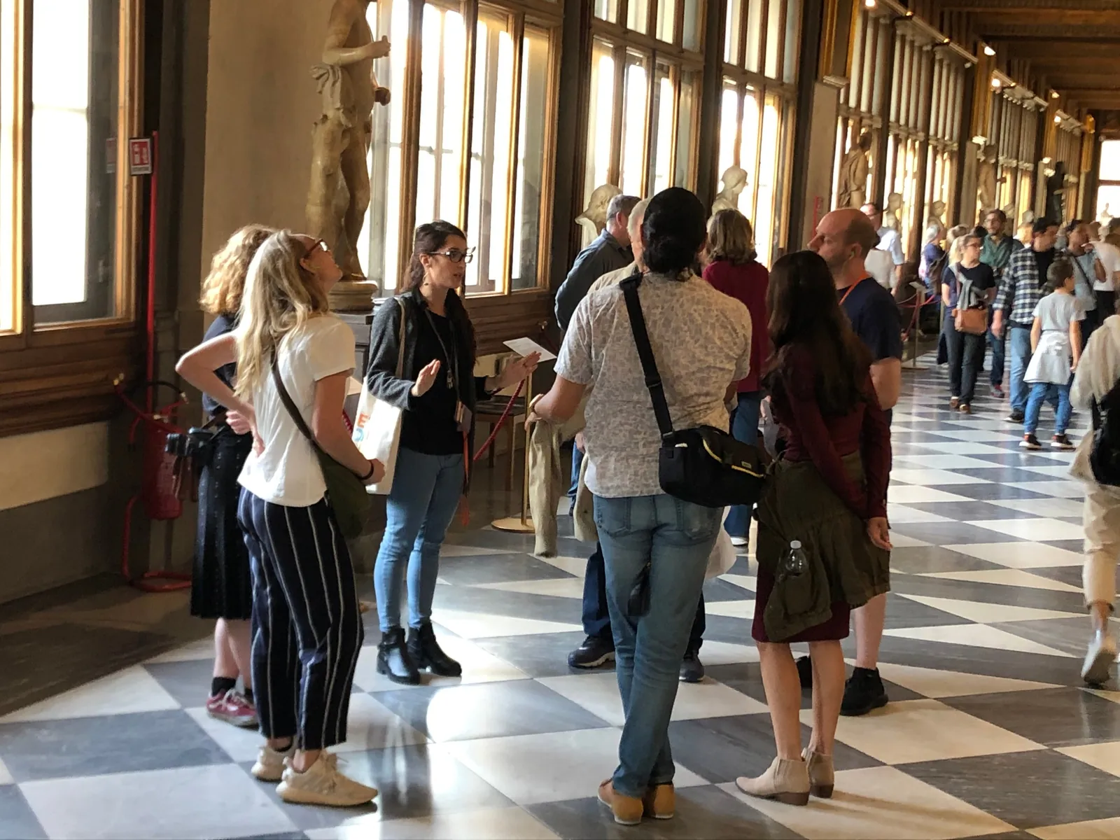 Small tour group in the Uffizi corridor with its chequered marble floor