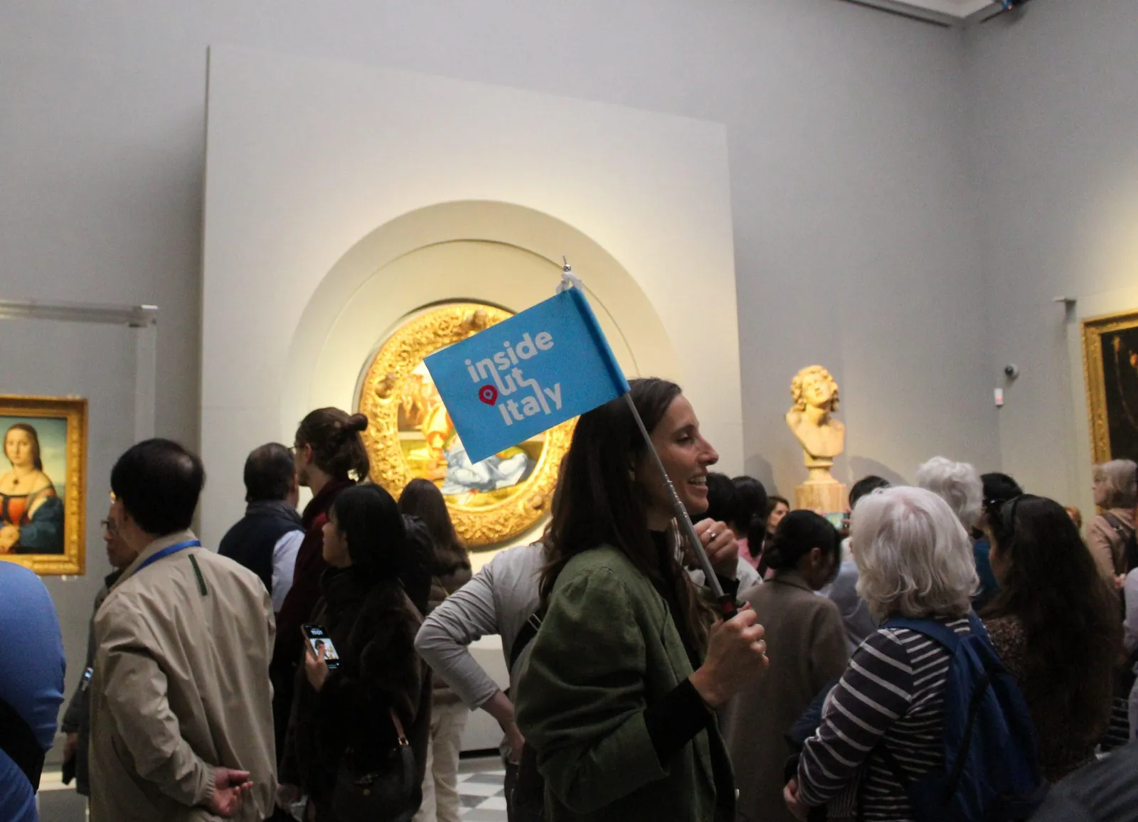 Guide with a blue flag leading a group past Michelangelo's Doni Tondo