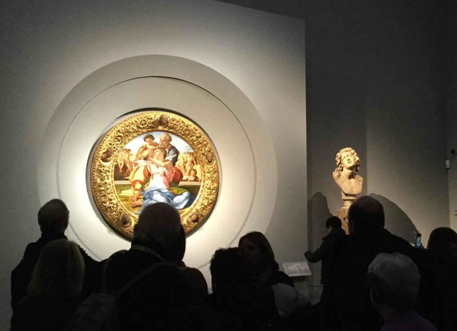 Visitors around Michelangelo's Doni Tondo in a darkened room