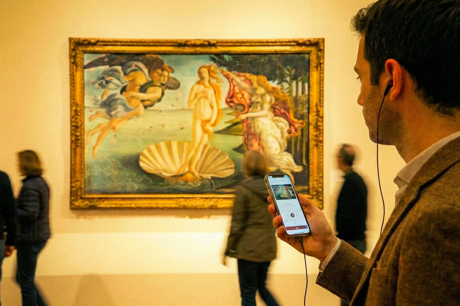 Visitor following the audio guide on a phone in front of Botticelli's Birth of Venus