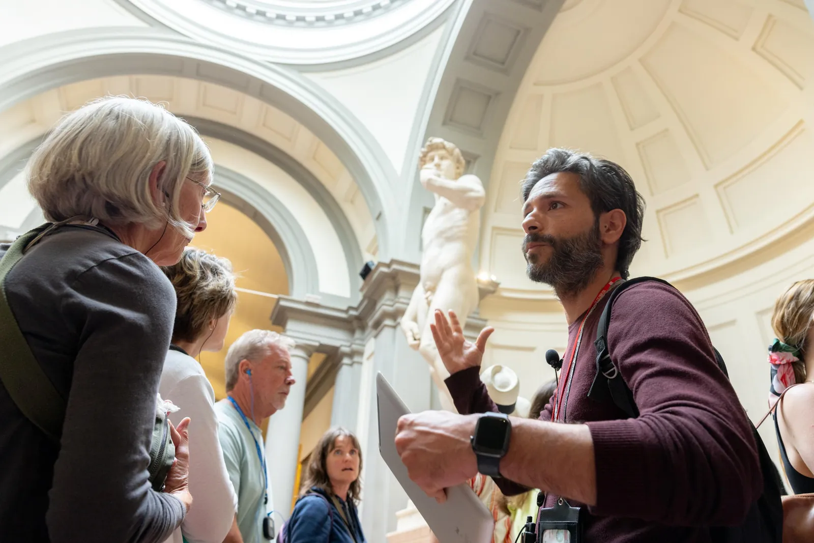 Guide pointing out details of Michelangelo's David to a small group