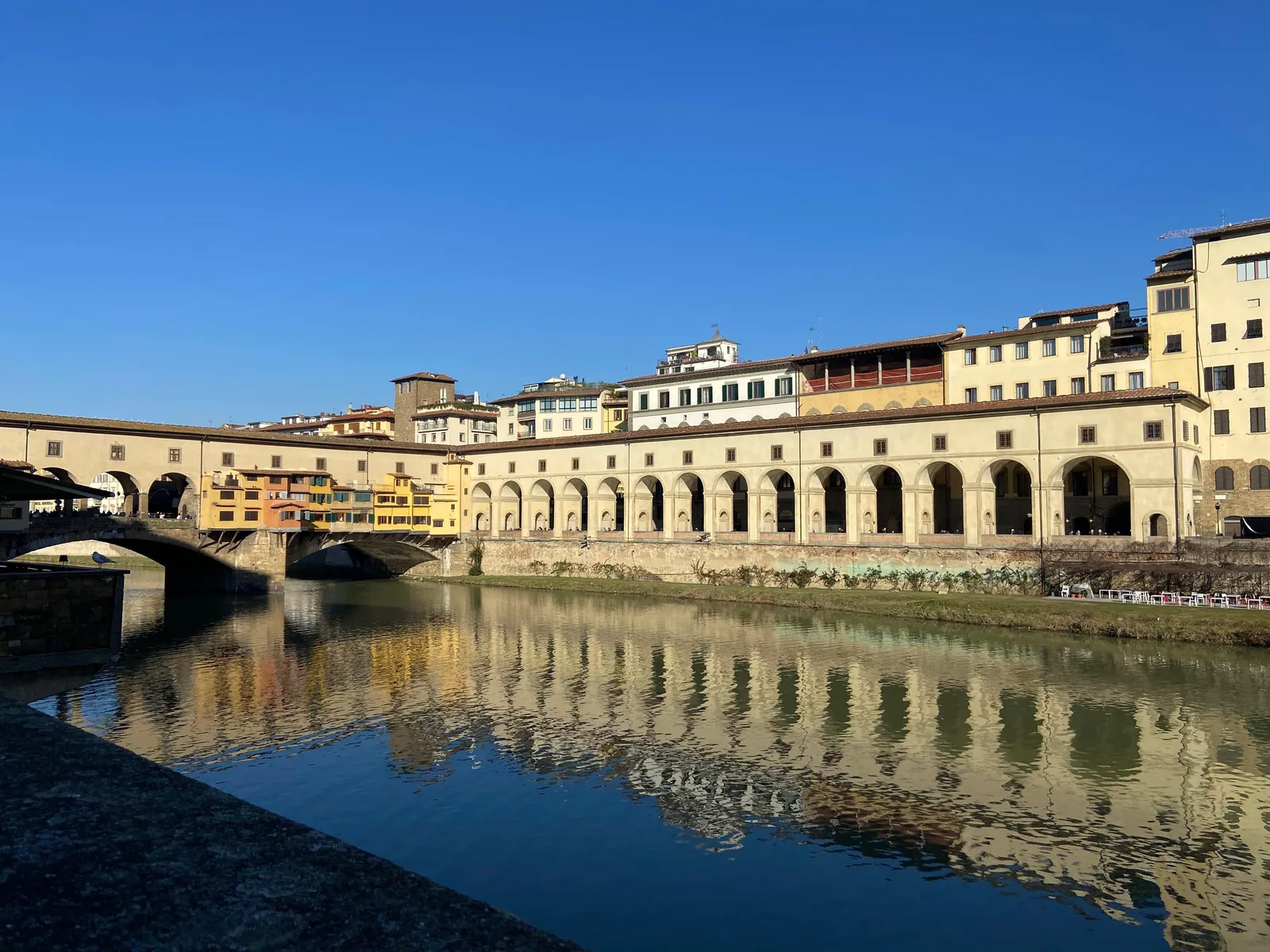 The corridor's riverside arcade reflected in the Arno