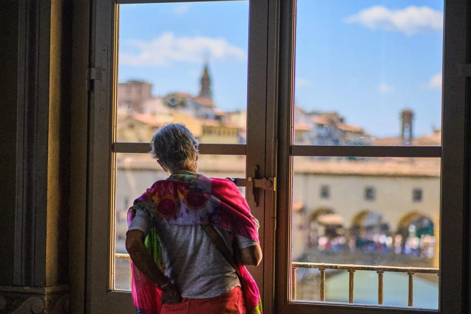 A visitor looking out at Ponte Vecchio from a gallery window