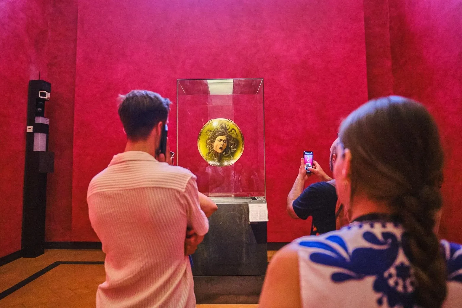 Visitors photographing Caravaggio's Medusa in its display case